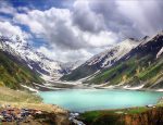 People enjoying a serene lake surrounded by mountains and greenery in Northern Pakistan