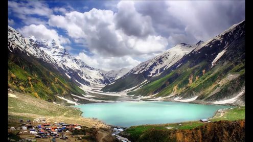 People enjoying a serene lake surrounded by mountains and greenery in Northern Pakistan